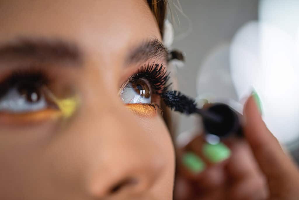 Nærbilde av jente som tar på mascara.